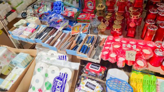 Verkaufsstand mit Haushaltswaren, Wischmops und Grablichtern auf dem griechischen Wochenmarkt